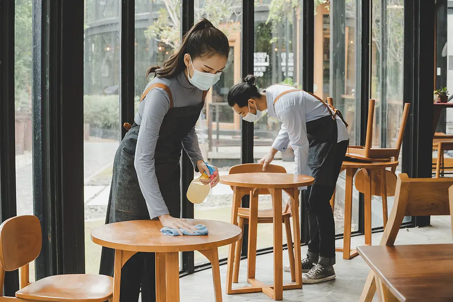 Commercial cleaning staff caring for tables and shared surfaces